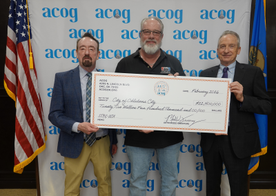 Image of three men holding a prop check representing transportation funding.