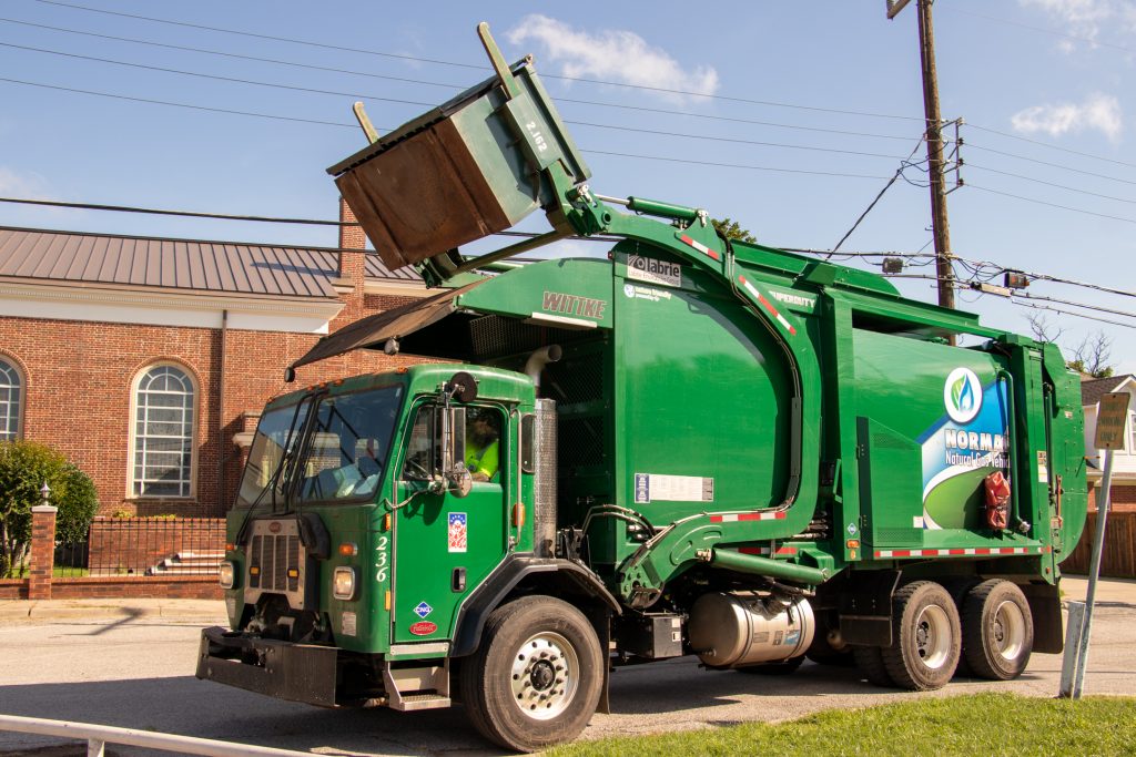 City of Norman compressed natural gas sanitation truck lifting a commercial waste container